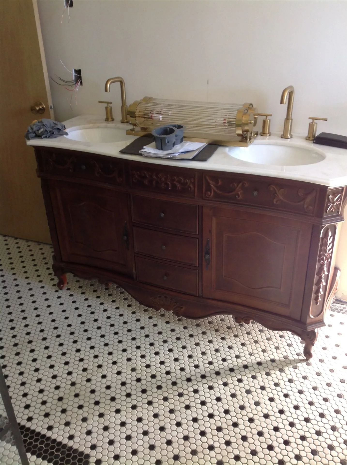 Antique vanity with gold fixtures and hex tile floor