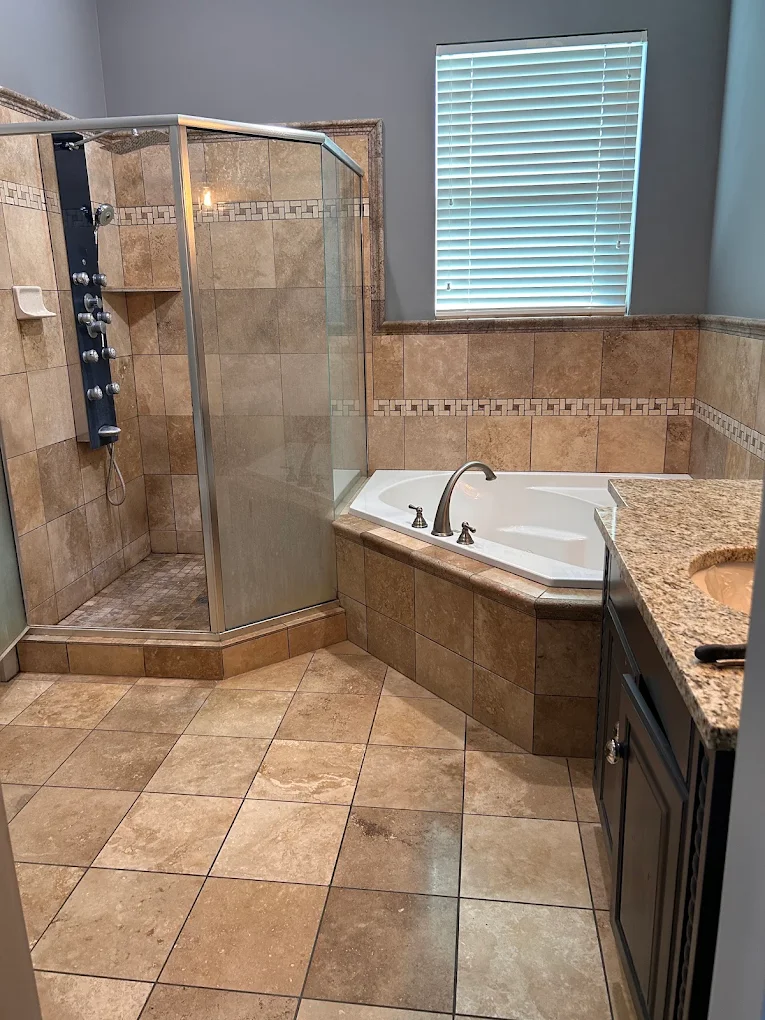 Remodeled bathroom with corner soaking tub, tiled shower enclosure, and granite vanity