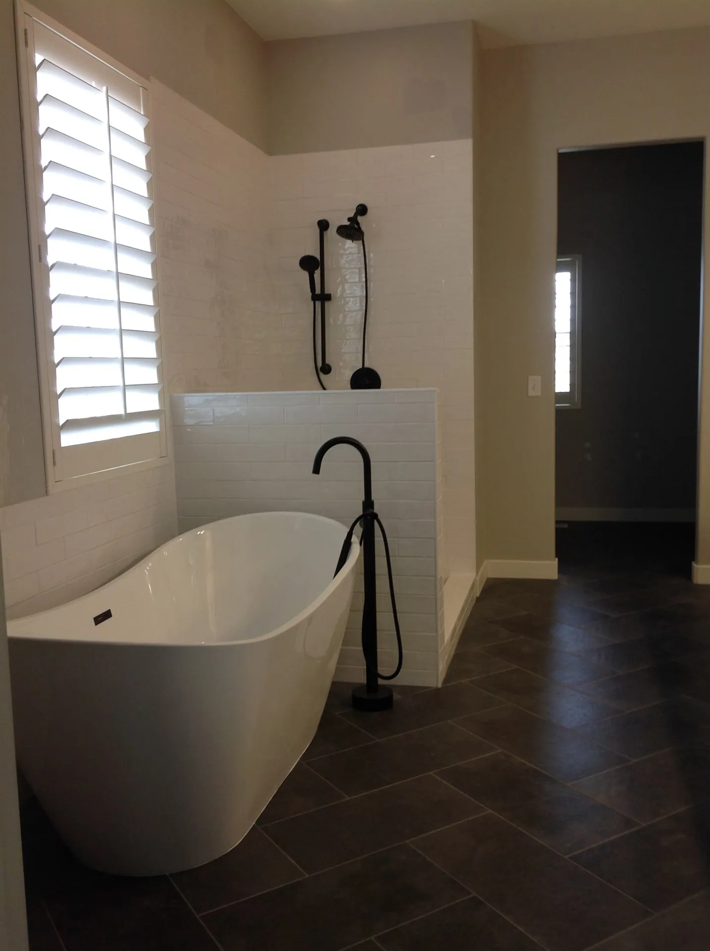 White tile shower with black fixtures and glass panel