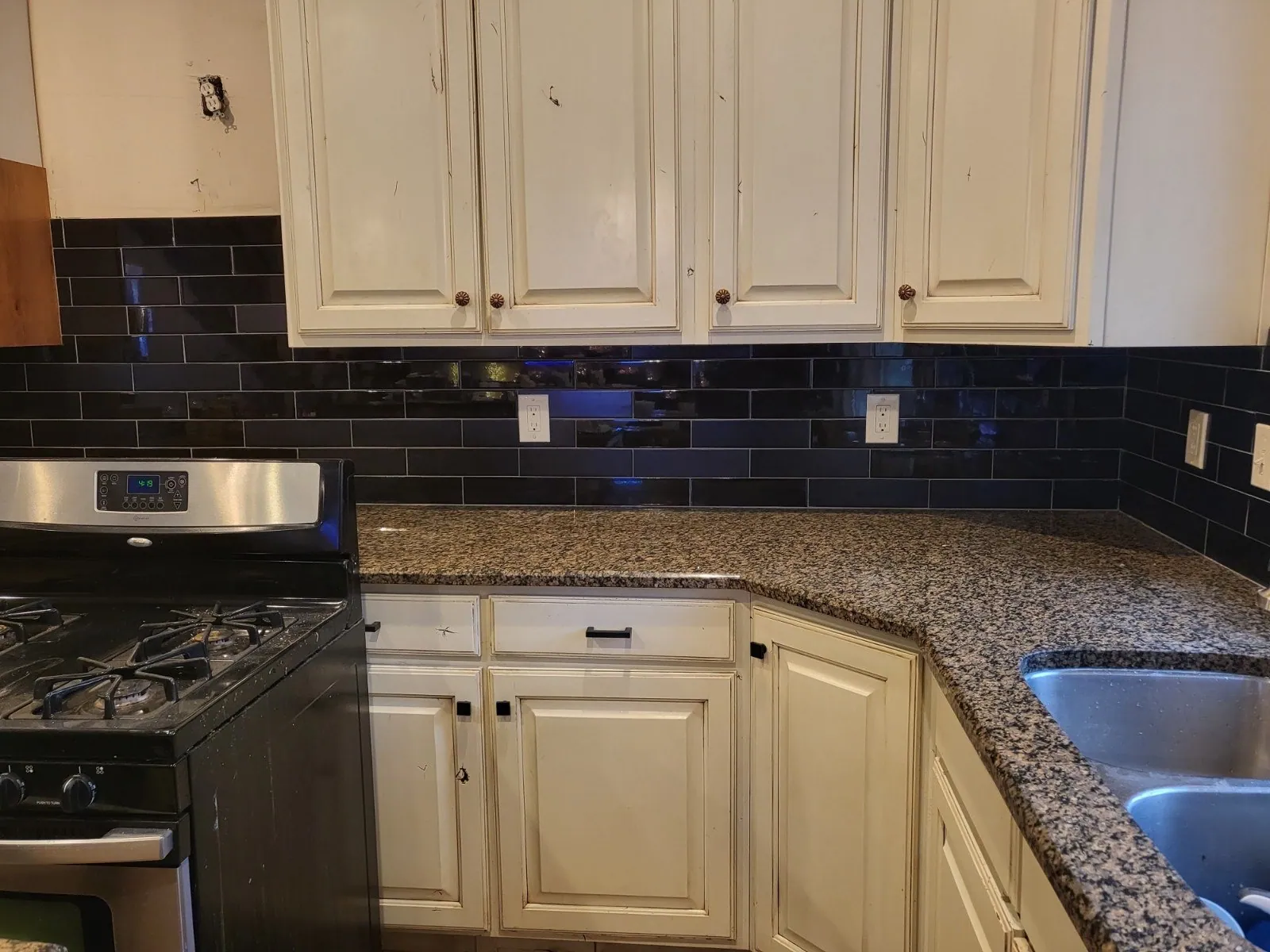 Kitchen with navy subway tile backsplash and granite counters