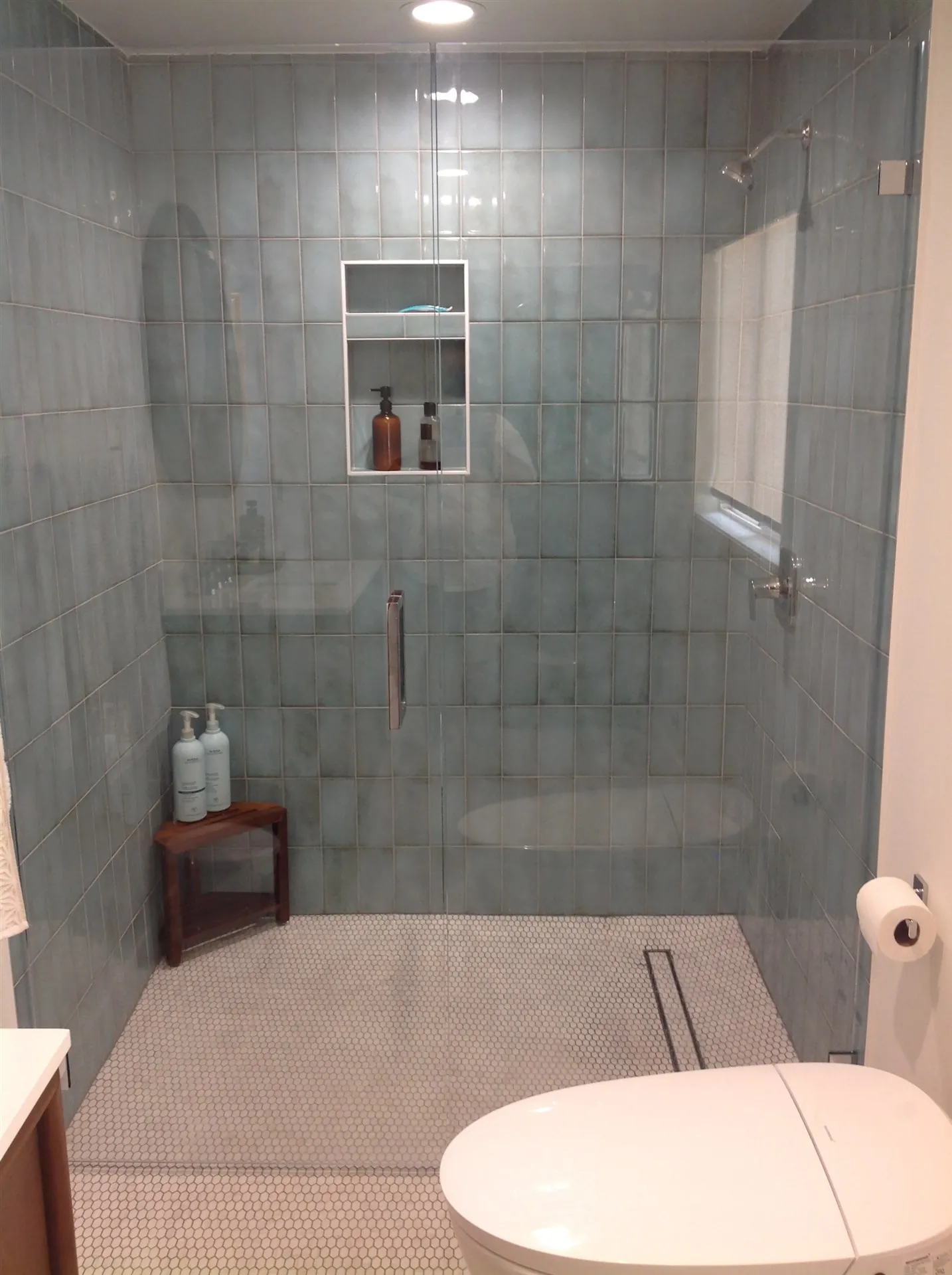 Large format grey tile shower with corner bench