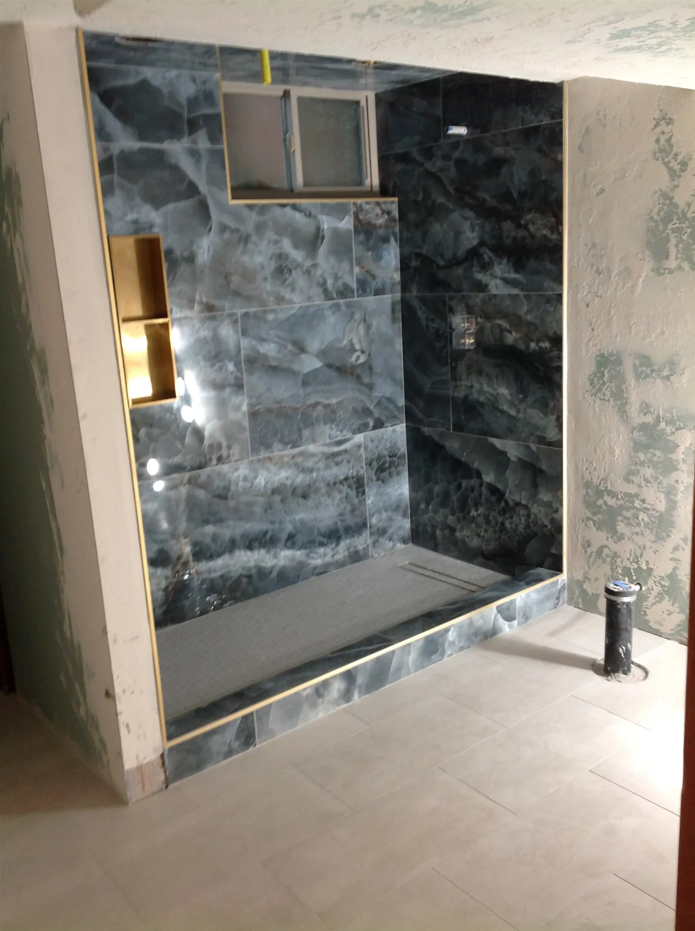 Grey marble slab shower with gold-trimmed niche
