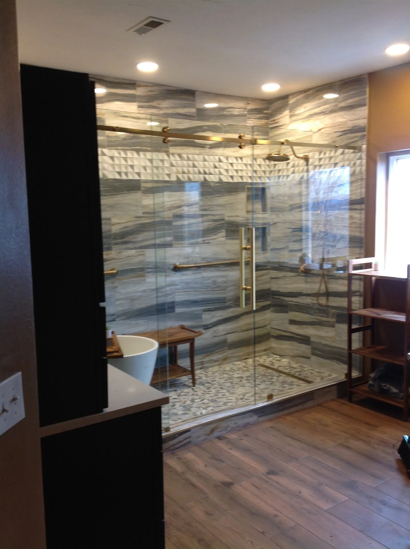 Luxury master bath with stone slab surround and gold fixtures