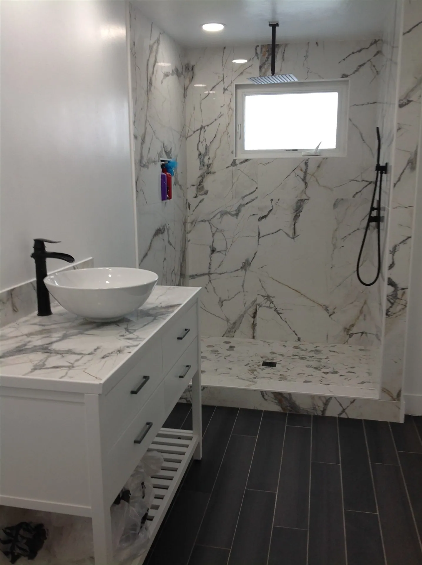Marble-look shower with vessel sink vanity and dark plank floor