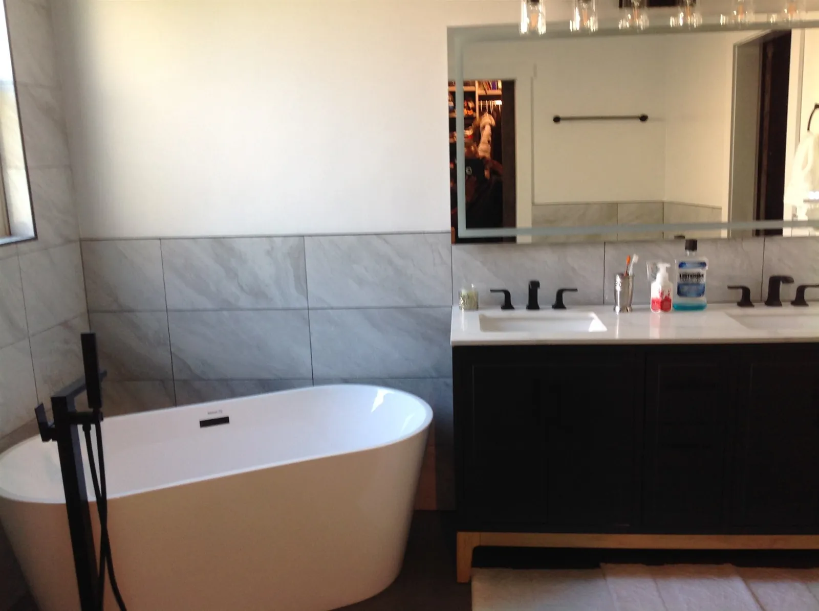 Freestanding tub with dark double vanity and grey tile