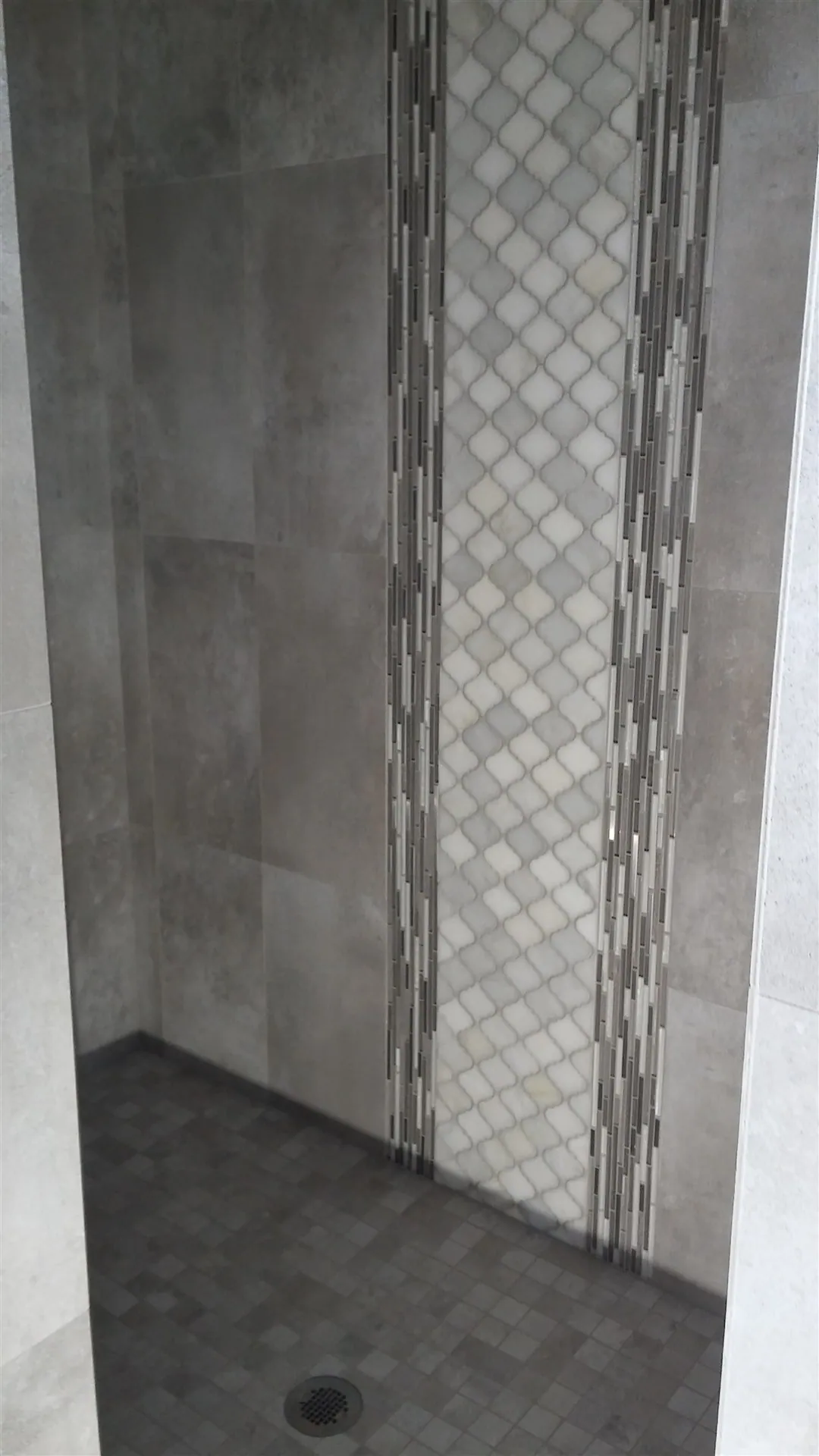 Walk-in shower with vertical tile and mosaic inset