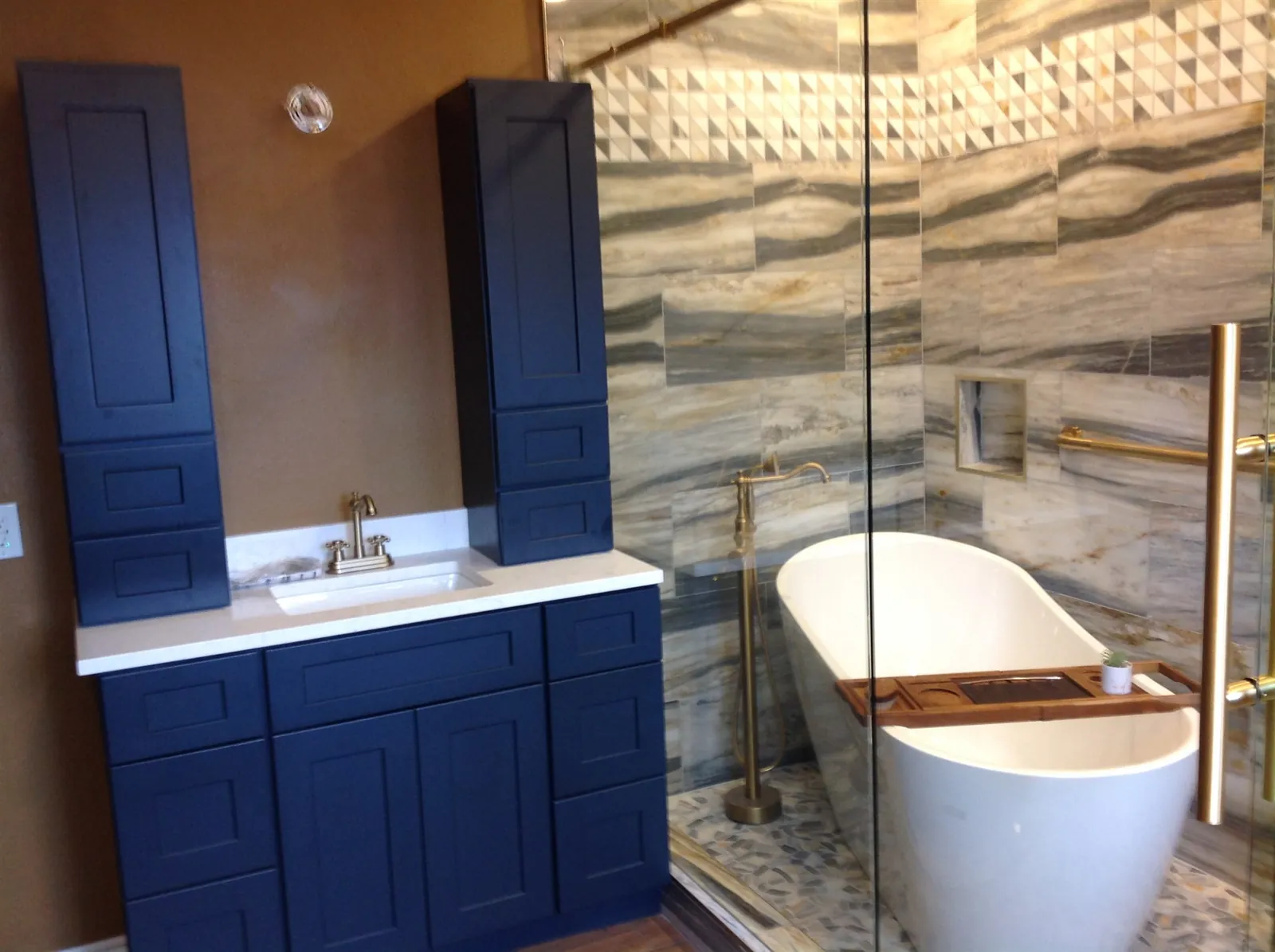 Navy vanity with quartzite slab walls and freestanding tub