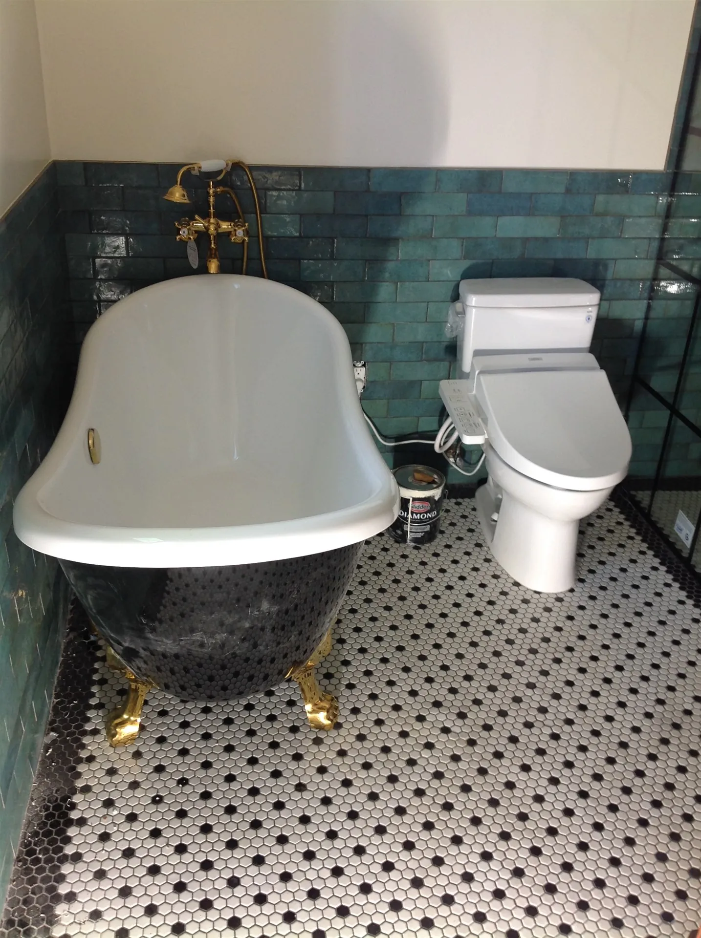Freestanding soaking tub with gold filler and mosaic floor