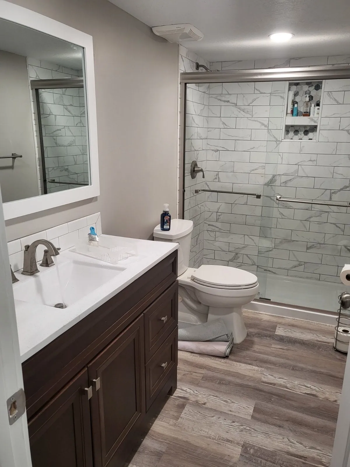 Bathroom with glass shower, vanity and wood-look floor