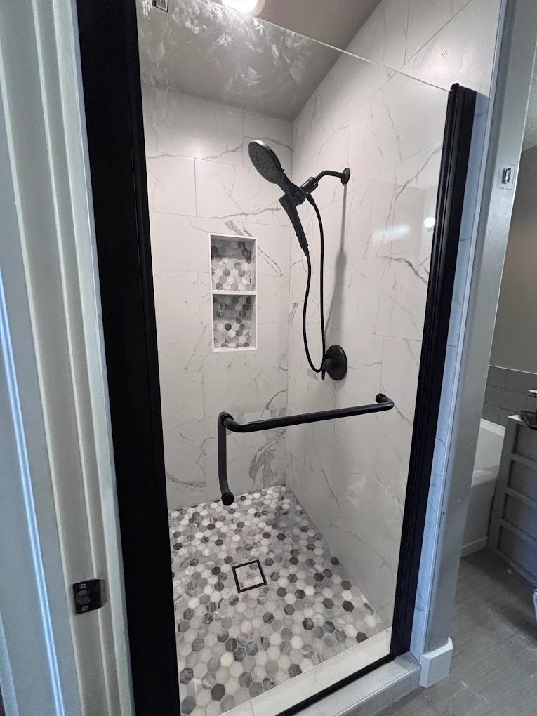 Walk-in shower remodel with marble-look tile, grab bar, and mosaic hexagon tile floor