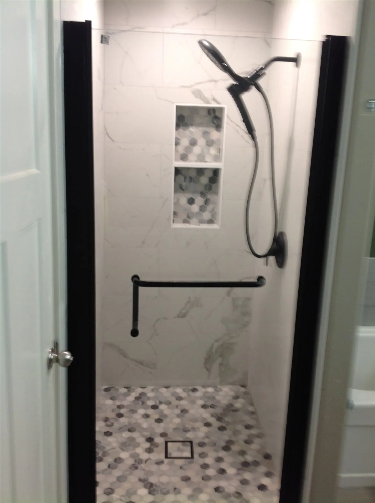 Marble-look shower with pebble floor and black fixtures