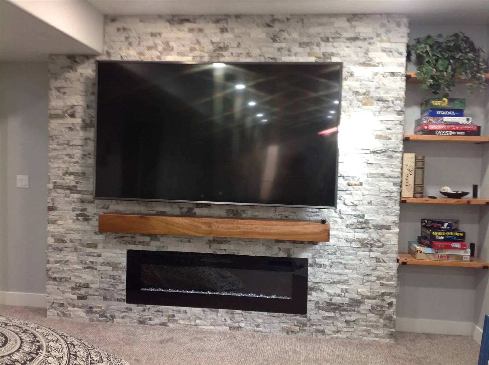 Stacked stone fireplace wall with floating shelves and linear fireplace