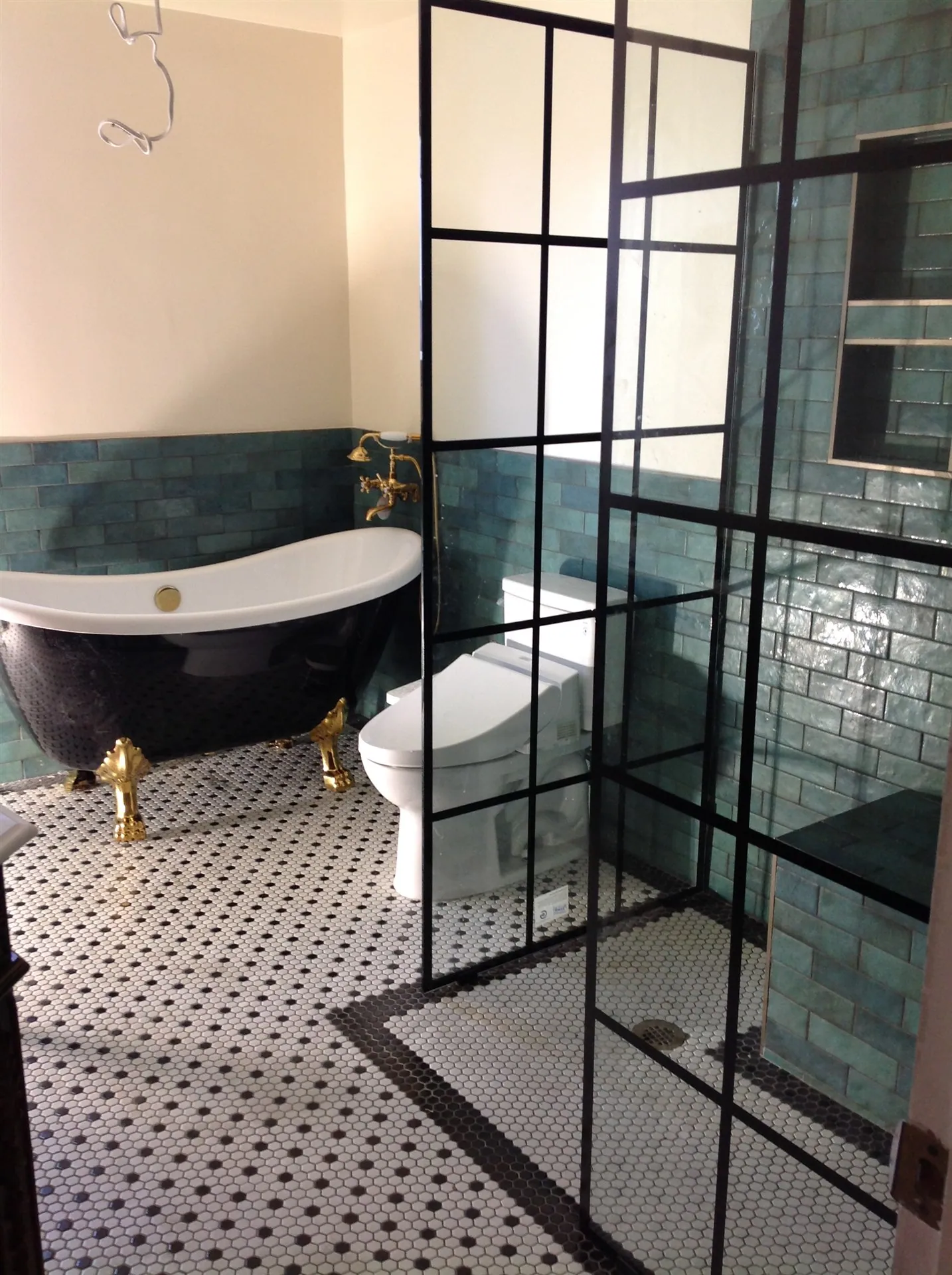 Teal zellige tile bathroom with gold fixtures and freestanding tub