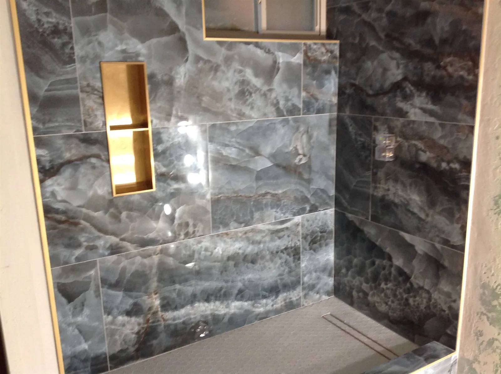 Stone slab shower wall with brass accent niche