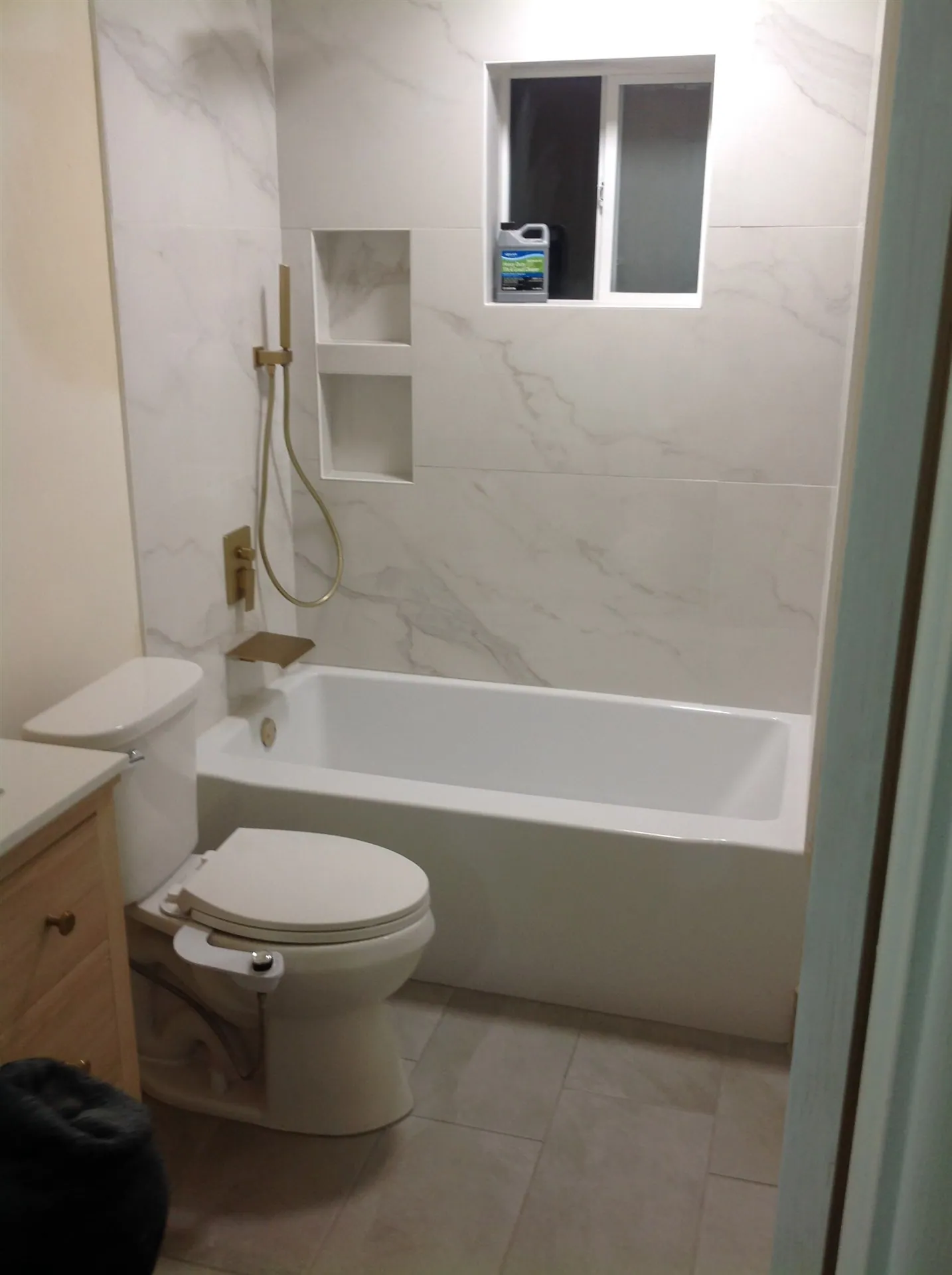 Marble-look tile shower with built-in niches and gold fixtures