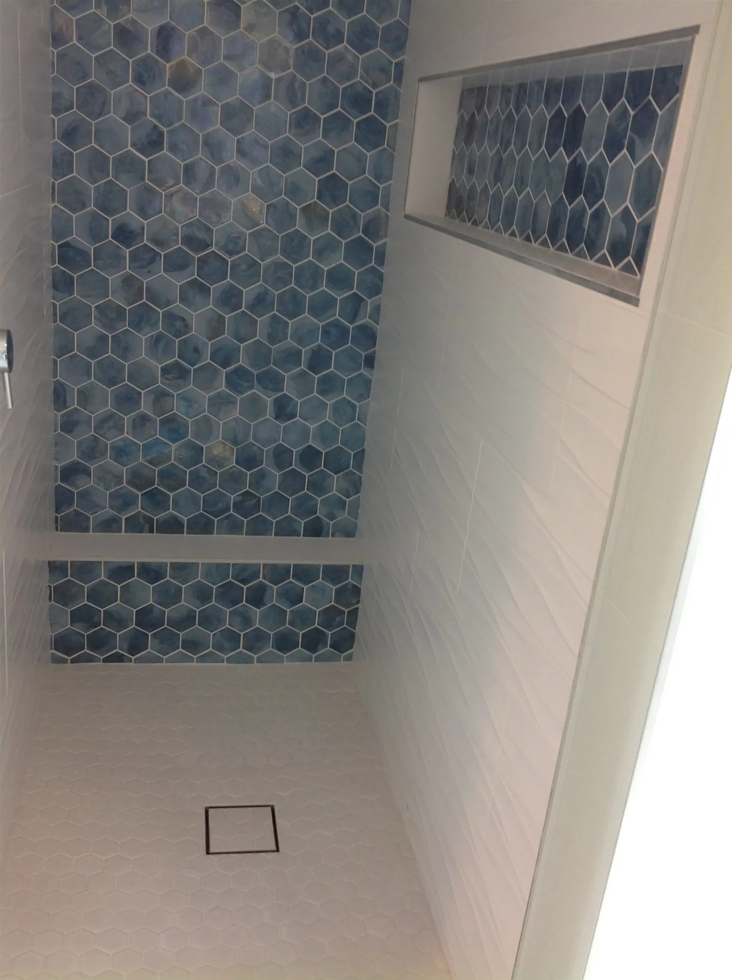 Blue penny-round tile shower with white walls