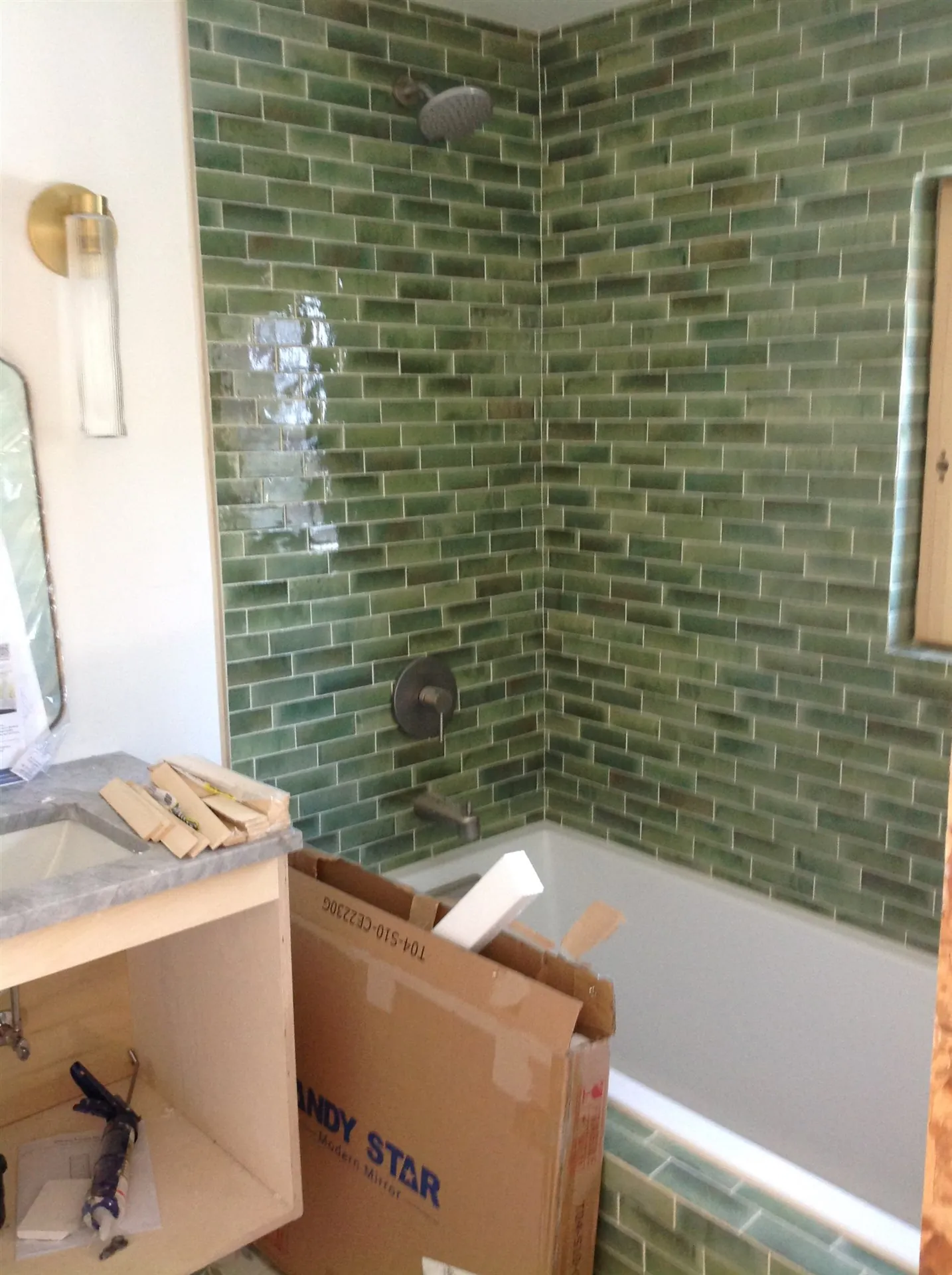 Green zellige tile tub surround with brass sconce