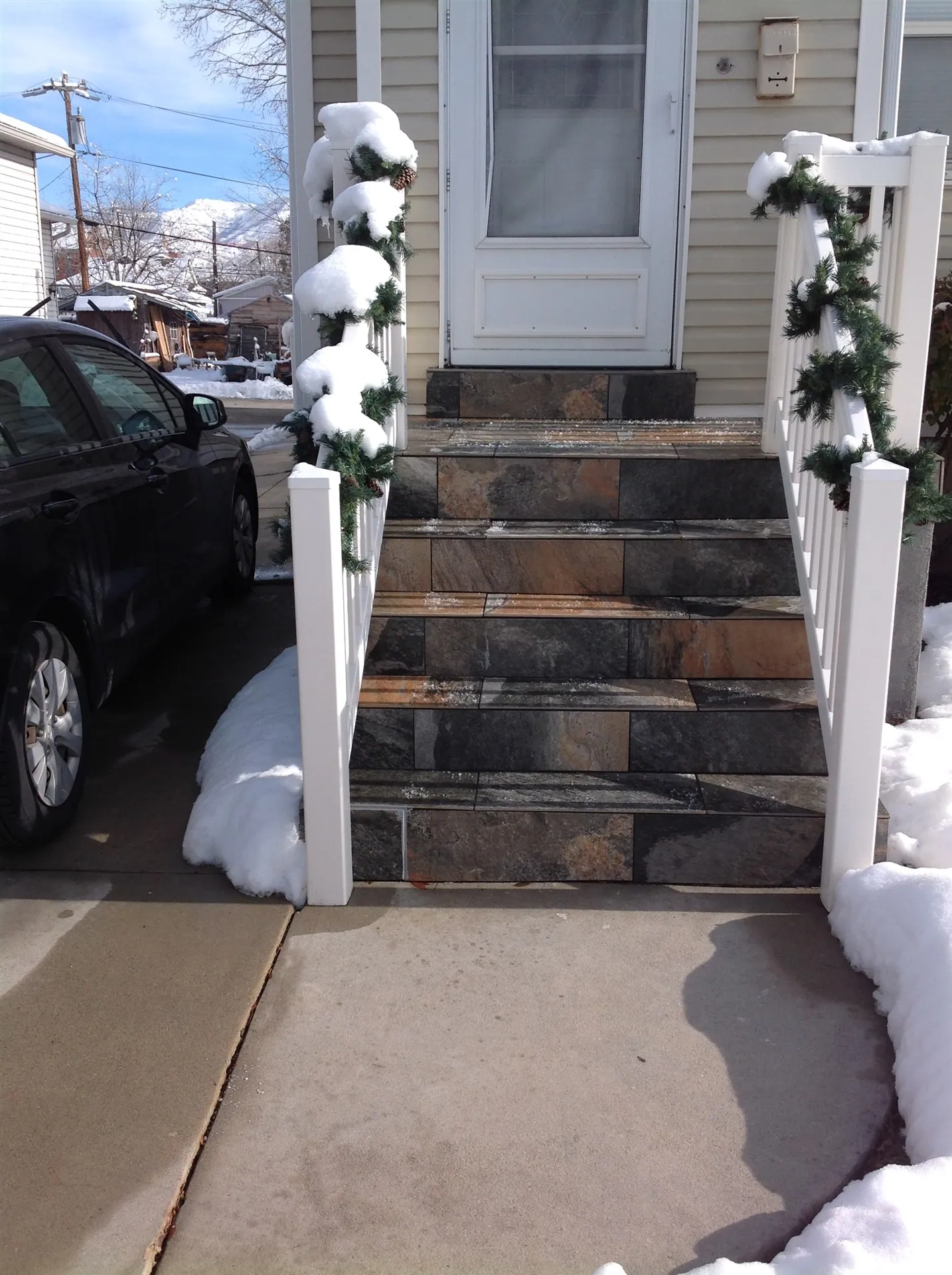 Stone tiled front steps with white railing