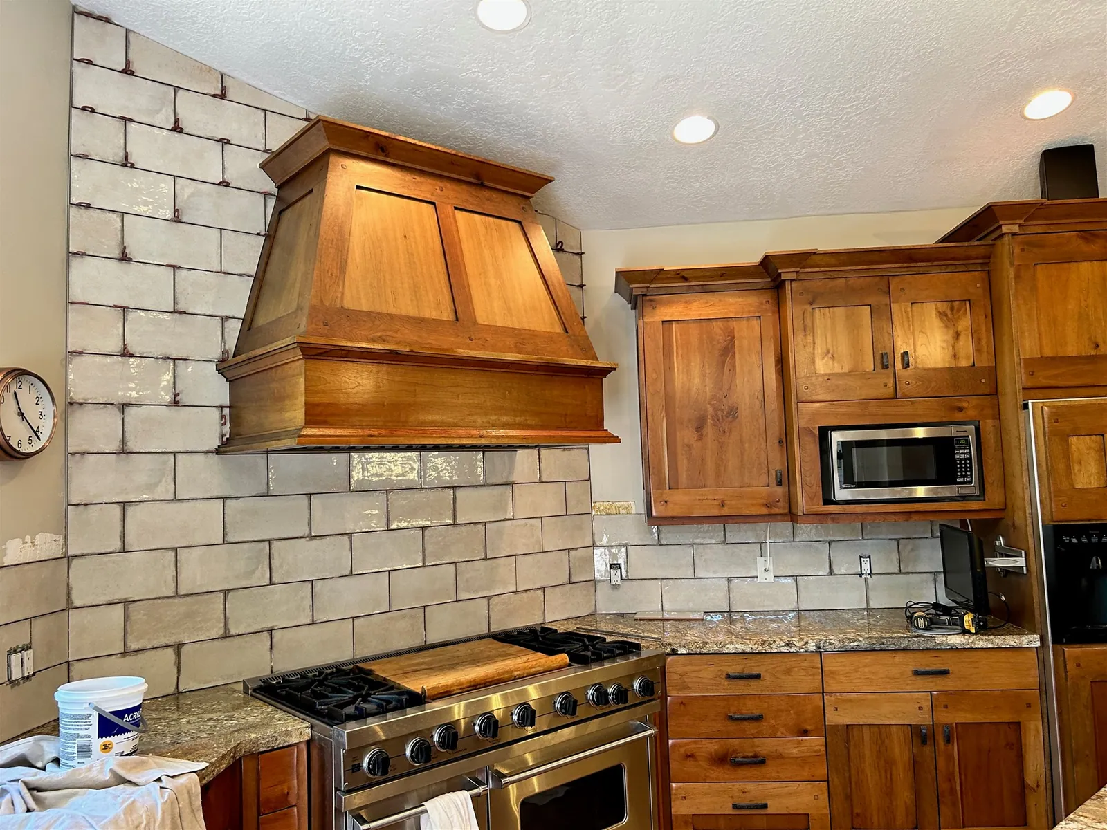 Kitchen with white subway backsplash and custom wood range hood